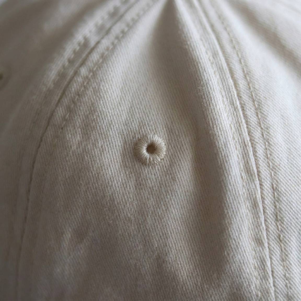 Macro of a sewn ventilation eyelet in the cream twill
