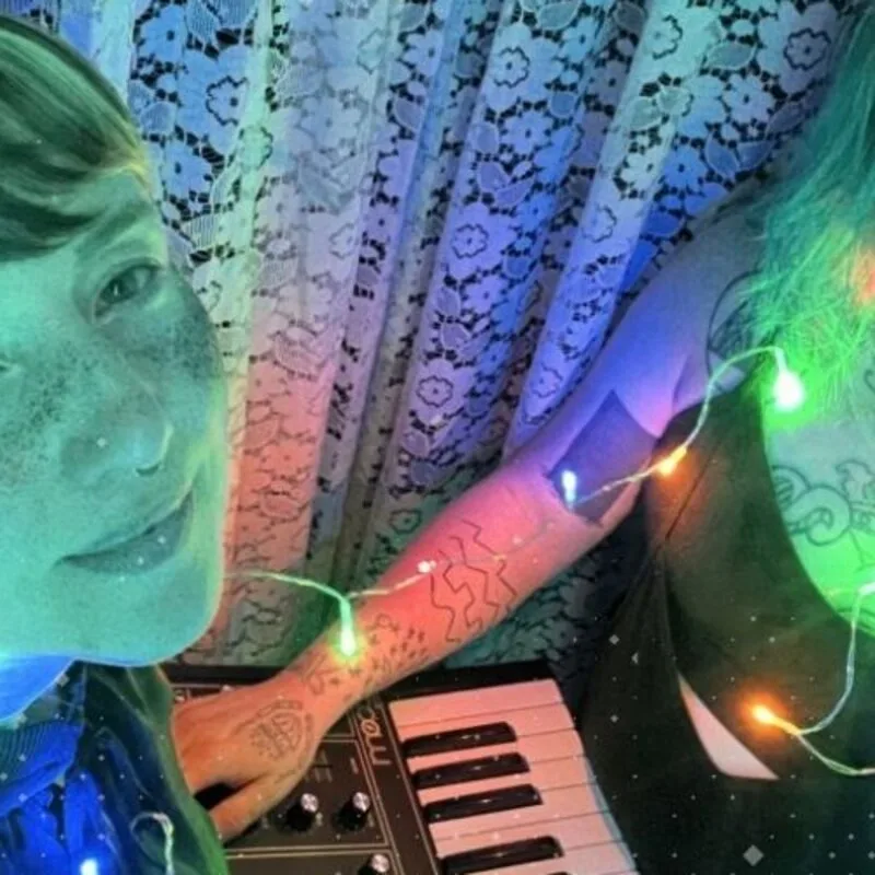 A SALTLAMP member at a synth under coloured string lights