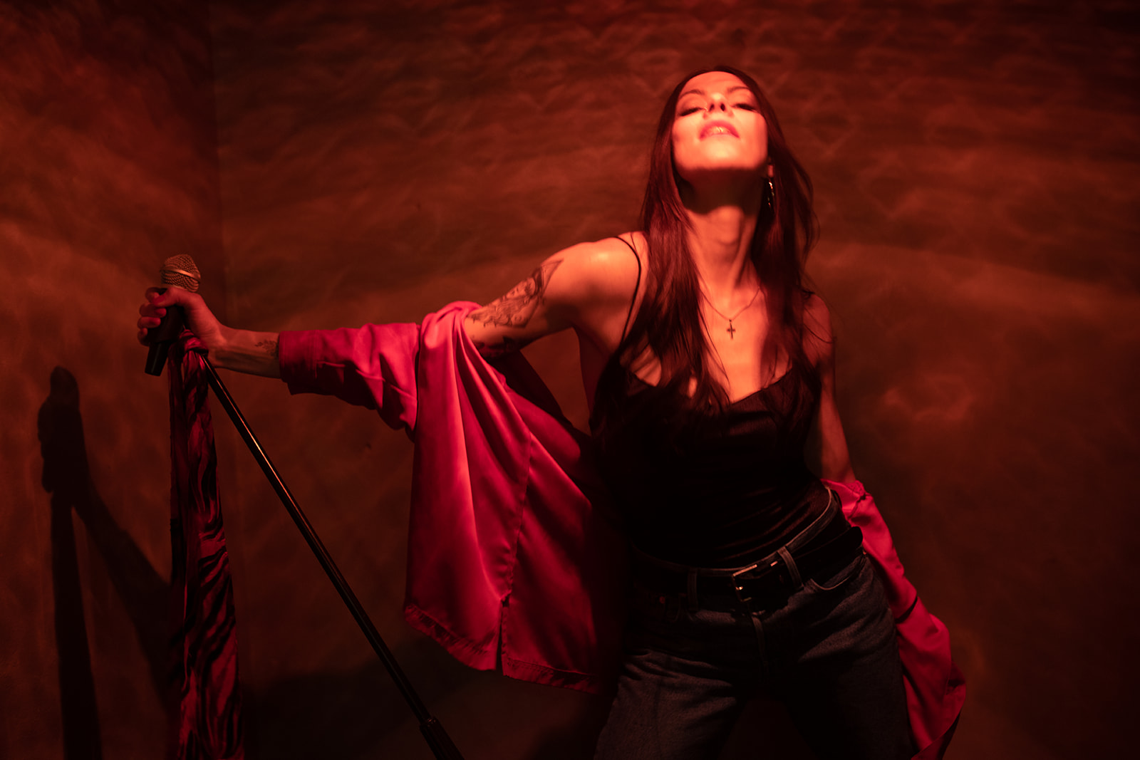 Elyse Aeryn on a stage in amber light, head tilted back, one hand gripping a mic stand