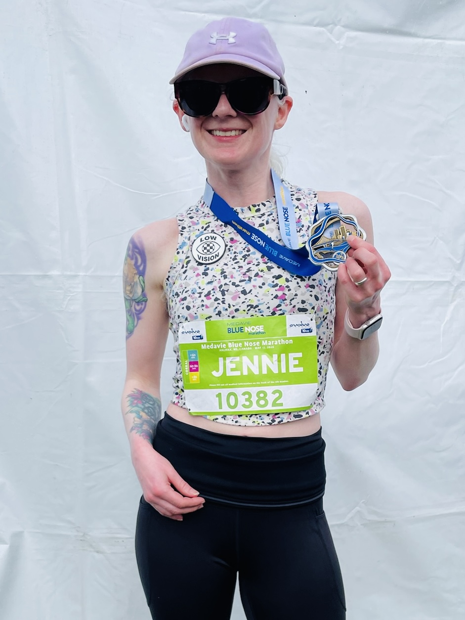 Jennie Bovard smiling with her Blue Nose 10K medal and a Low Vision button on her top
