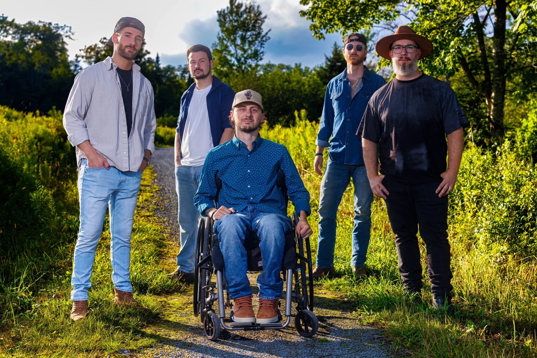 Connor Hirtle seated in his wheelchair with the four other members of HIRTLE standing around him outdoors